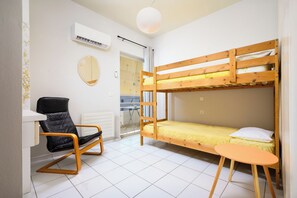 Ein kleines Zimmer mit Etagenbett, Stuhl, kleinem Tisch und Heizkörper.