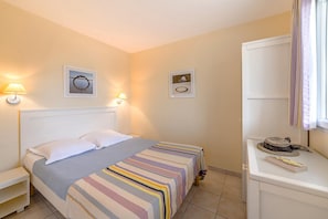A hotel room with a bed, bedside tables, a dresser, and wall-mounted lamps. - Oceanfront Suite for Five (Les Sables-d'Olonne)