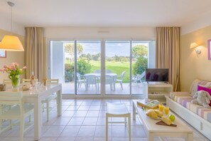 A hotel room with a dining area, a sofa, a television, and a view of the outdoors. - Oceanfront Suite for Five (Les Sables-d'Olonne)