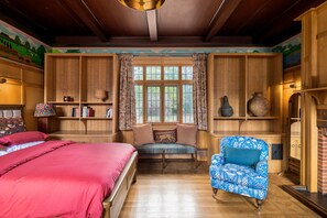 Ein gemütliches Zimmer mit einem Bett, einem blauen Sessel und einem Fenster mit Vorhängen.