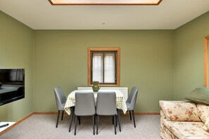 Een eethoek met een tafel, stoelen, een televisie en een bank.