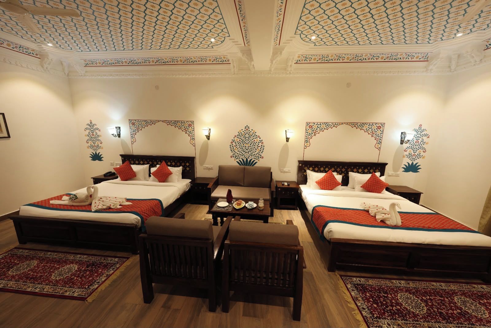 Una habitación de hotel con dos camas, zona de estar y decoración artística en la pared.