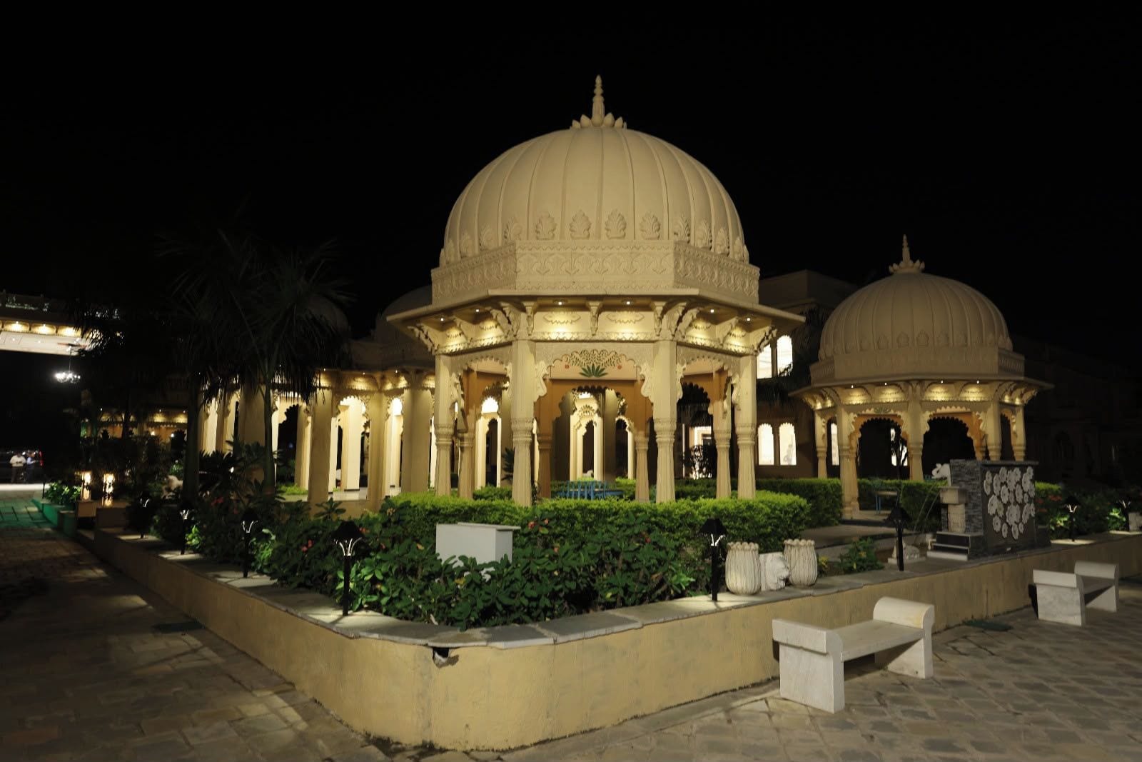 A traditional building with a large central dome and smaller domes, surrounded by a garden with benches and pathways.