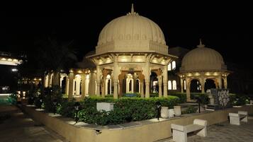 A traditional building with a large central dome and smaller domes, surrounded by a garden with benches and pathways.