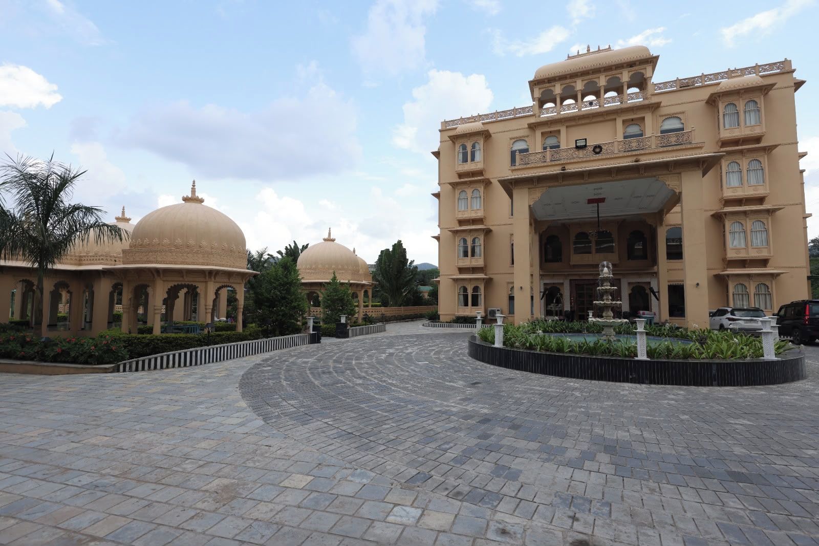 A large building with multiple domes and a fountain in the courtyard.