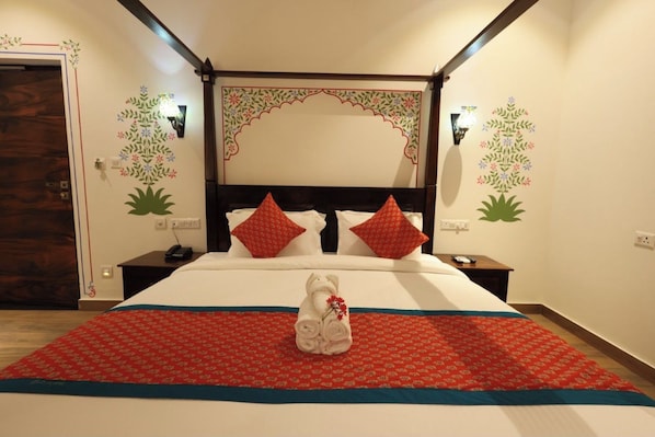 A hotel room with a four-poster bed, red and white bedding, a towel with a flower, and decorative wall art. - Tathastu Heritage Resort (Udaipur)