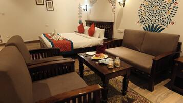 Ein Hotelzimmer mit einem Bett, zwei Sofas, einem Couchtisch mit Frühstücksangebot und dekorativer Wandgestaltung.