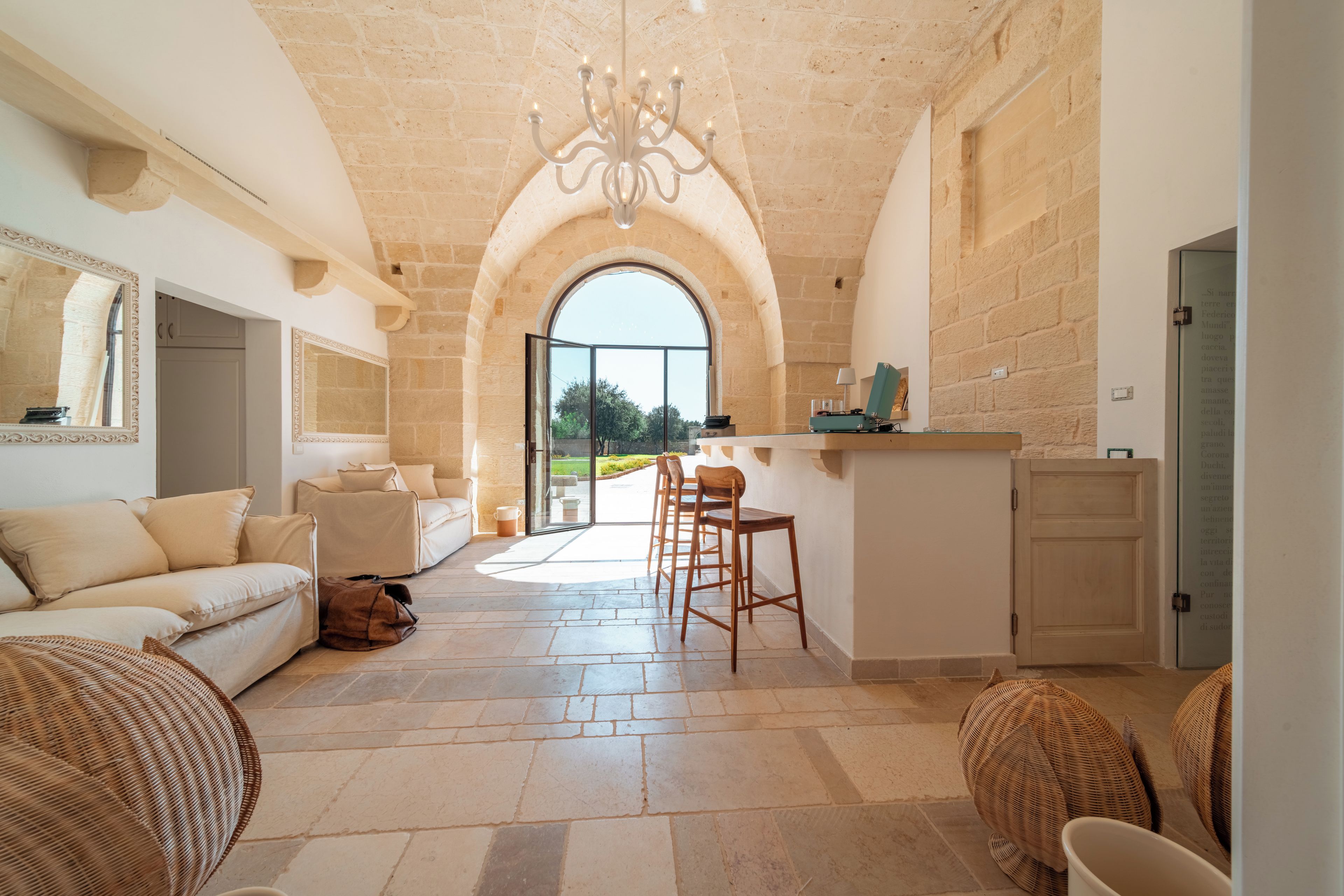 A spacious living area with a high ceiling, a dining area with a view, and a kitchen with stone walls.
