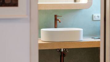 A bathroom with a white sink, a mirror, and two brown mugs on the floor.