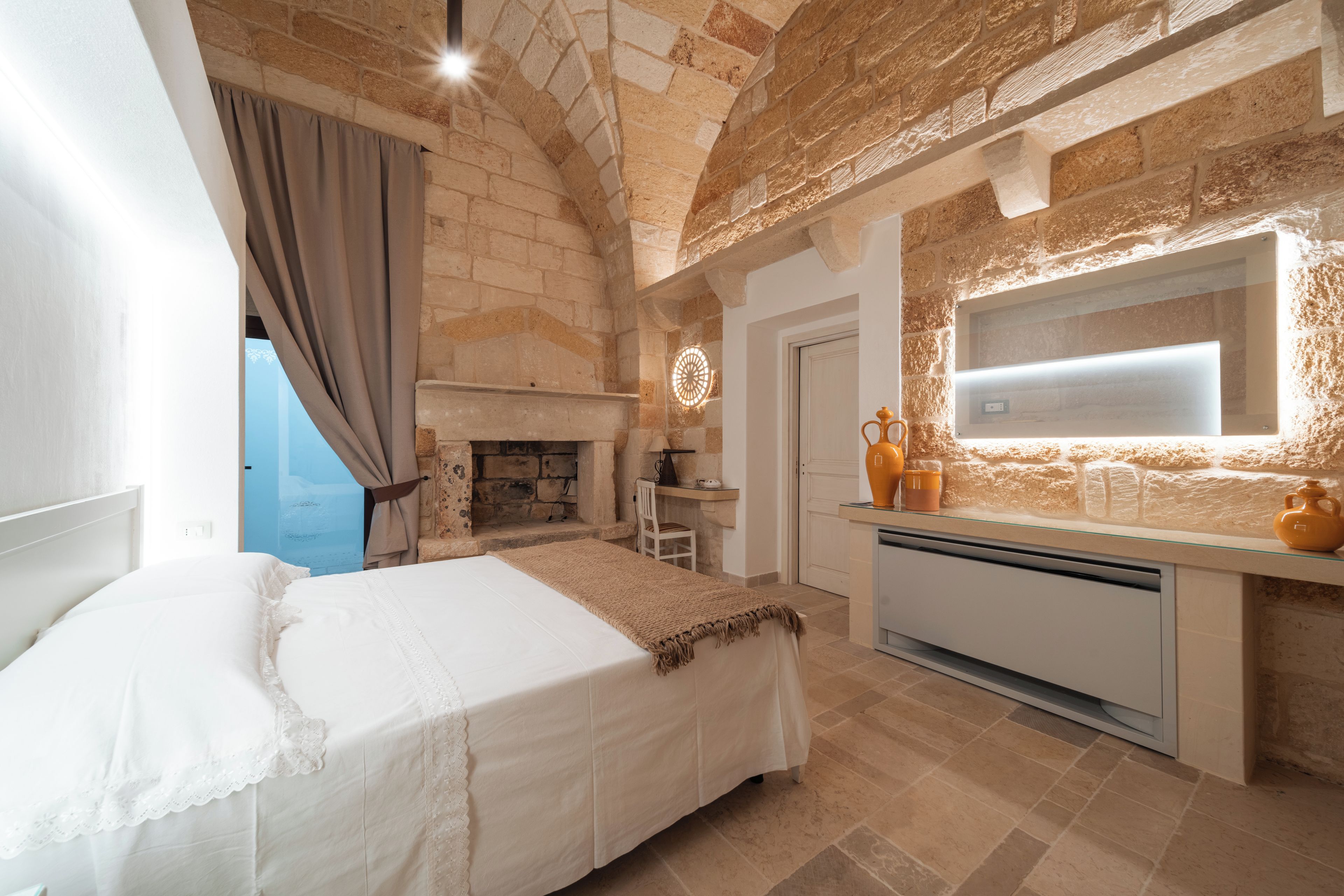 Un dormitorio con cama, chimenea, escritorio y ventana.