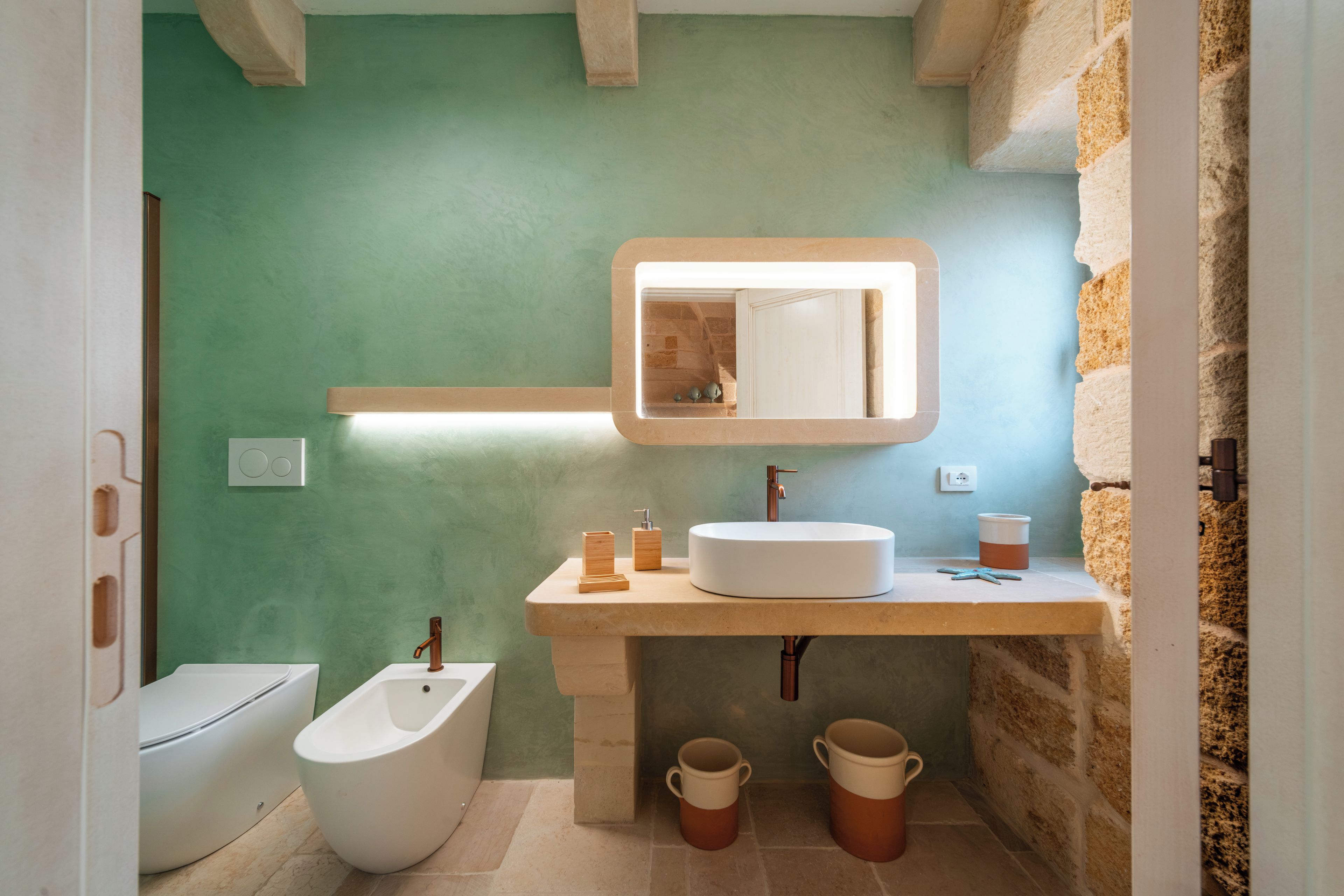 Un baño moderno con un bidé blanco, un espejo grande y un lavamanos con grifo.