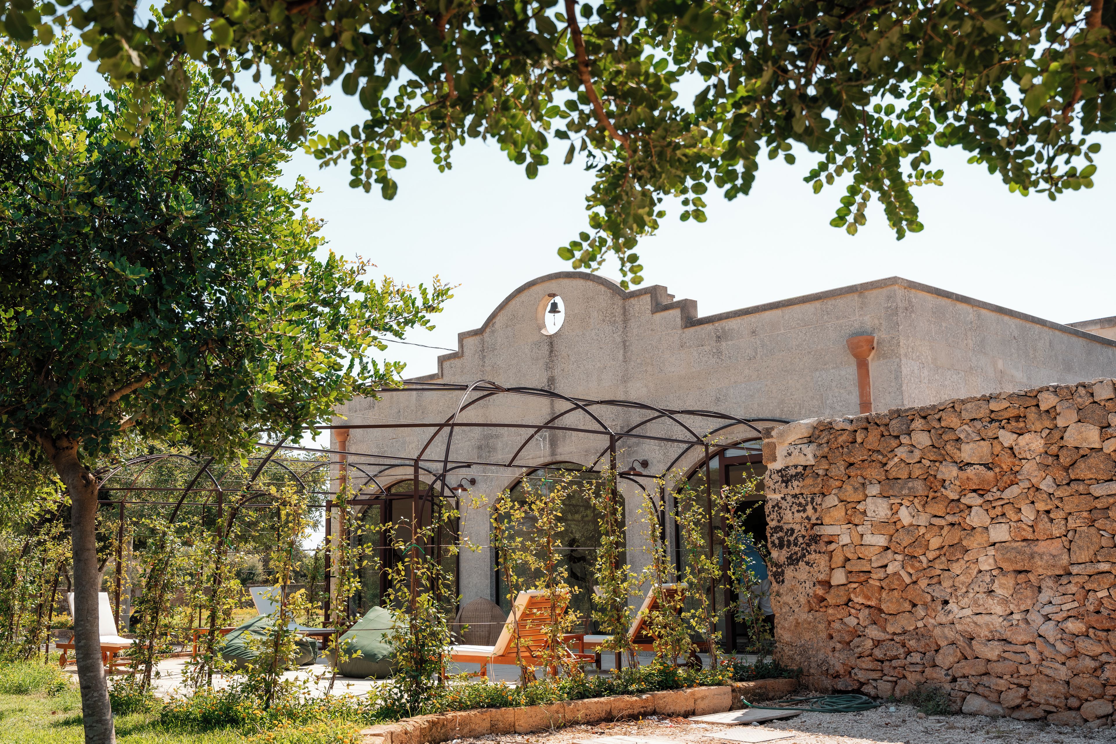 Un edificio con un muro in pietra e un arco in metallo.