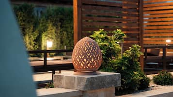 A decorative spherical object on a stone pedestal, surrounded by greenery and wooden structures.