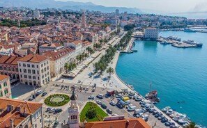 A coastal cityscape with a prominent waterfront promenade, a central roundabout, and a mix of historic and modern buildings. - Apartment with large garden in the heart of Split (Split)