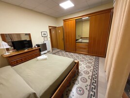 Una habitación de hotel con cama, televisión, cómoda, espejo y armario.