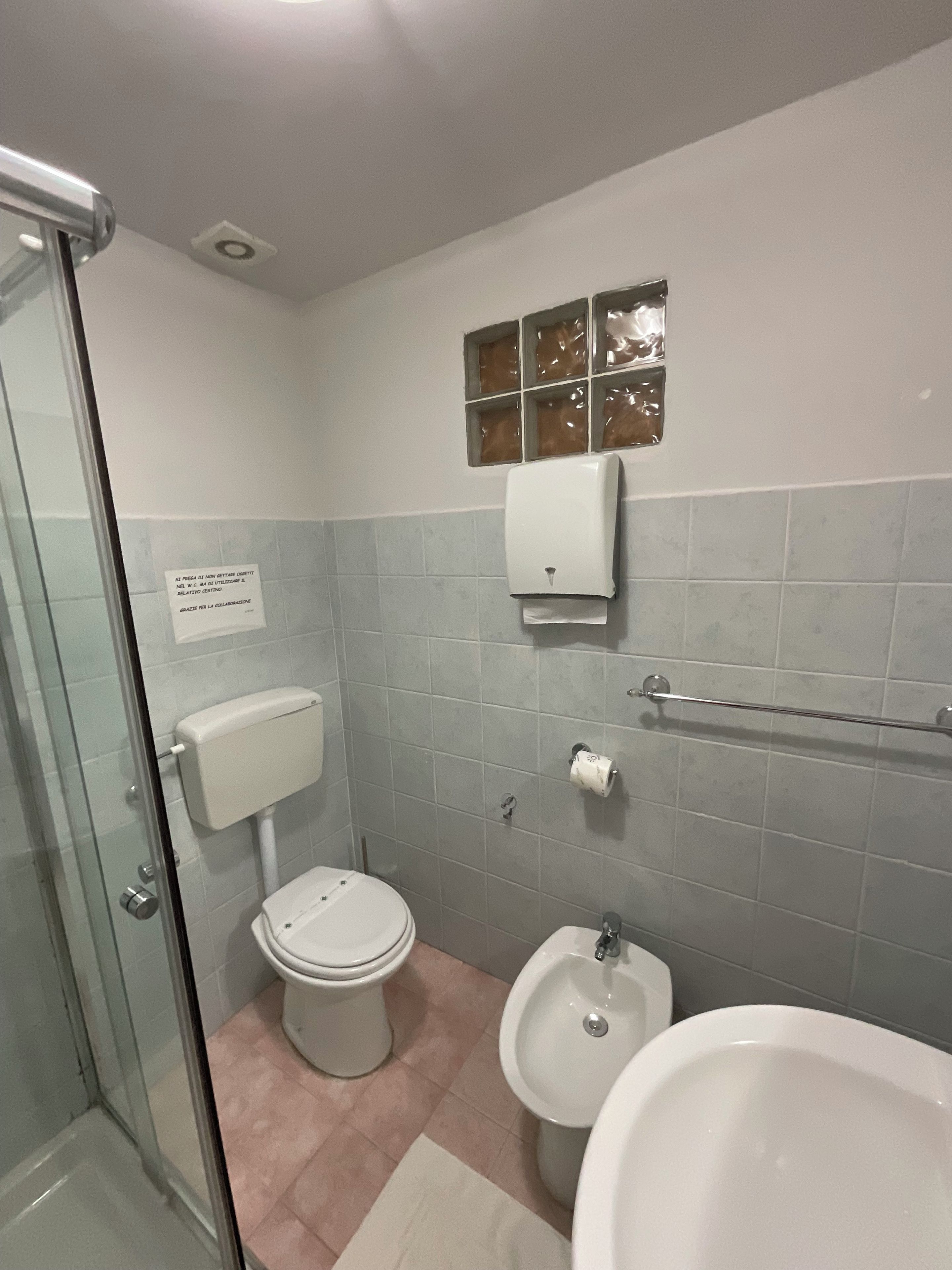 Une salle de bain comprenant des toilettes, un bidet et une douche séparée par une paroi en verre.