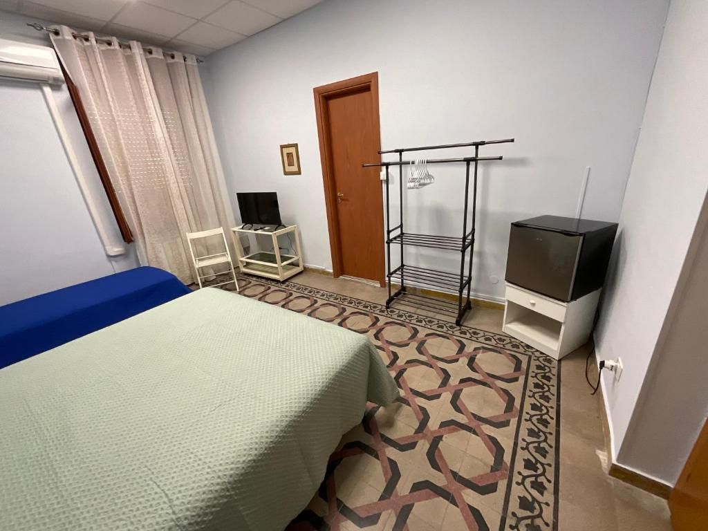 A hotel room with a bed, a TV, a wardrobe, and a small table.