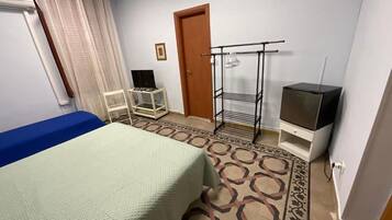 A hotel room with a bed, a TV, a wardrobe, and a small table.