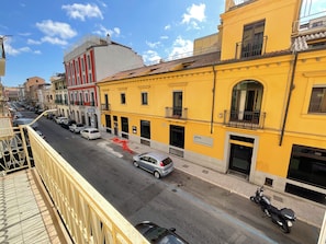 Vista de la calle con edificios amarillos, coches aparcados y una motocicleta.