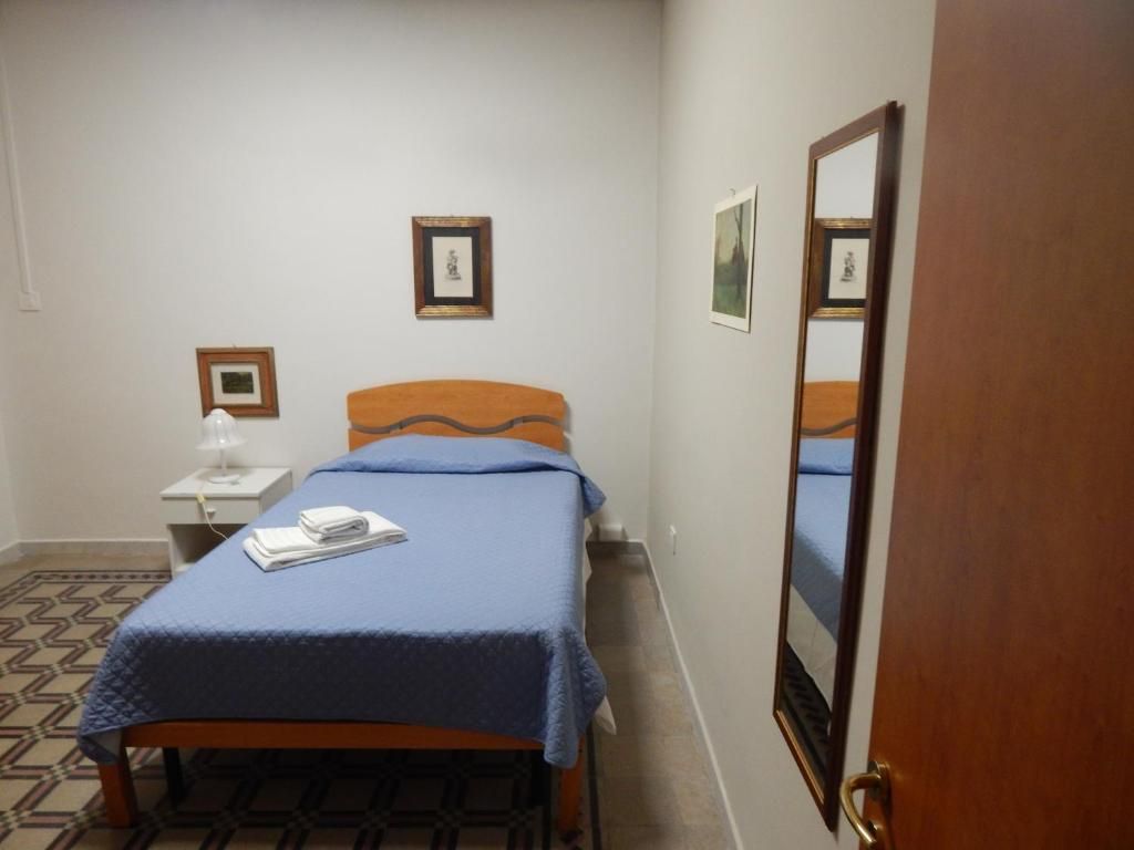 A bedroom with a bed, a bedside table, a lamp, and framed pictures on the wall.