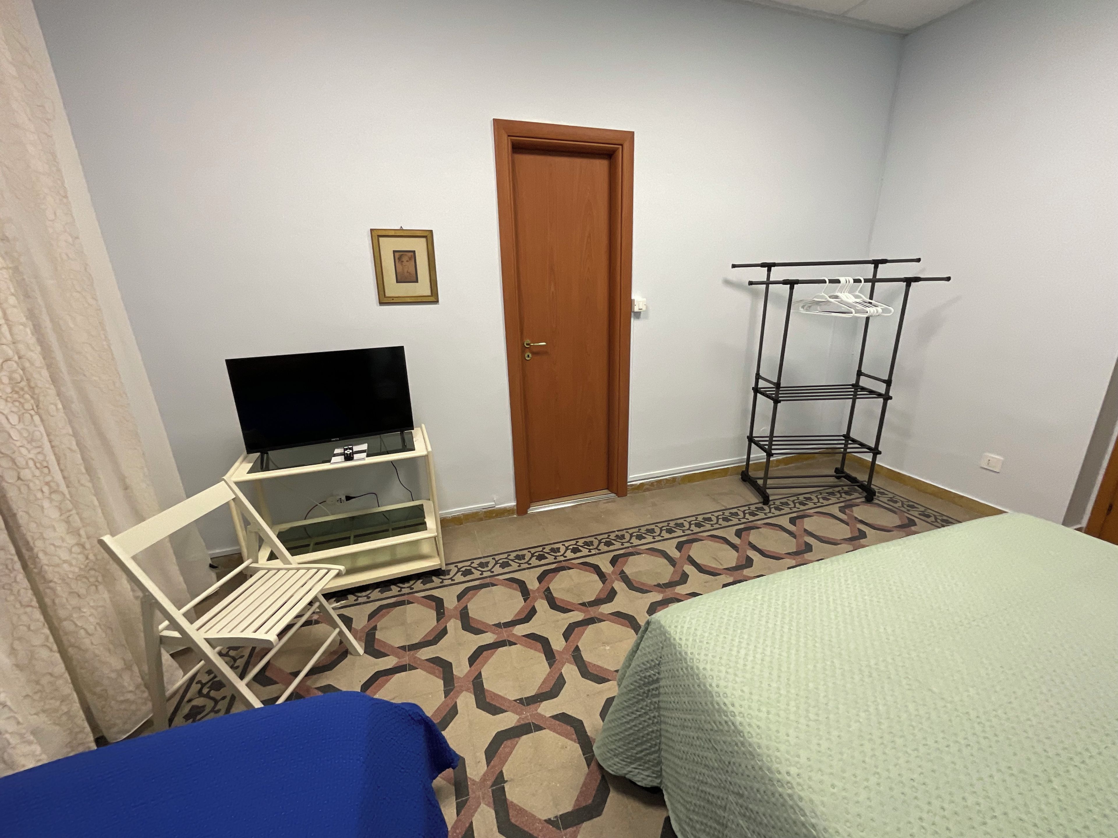 Ein Hotelzimmer mit einem Bett, einem Fernseher auf einem Schrank, einem Kleiderschrank und einem gemusterten Teppich.