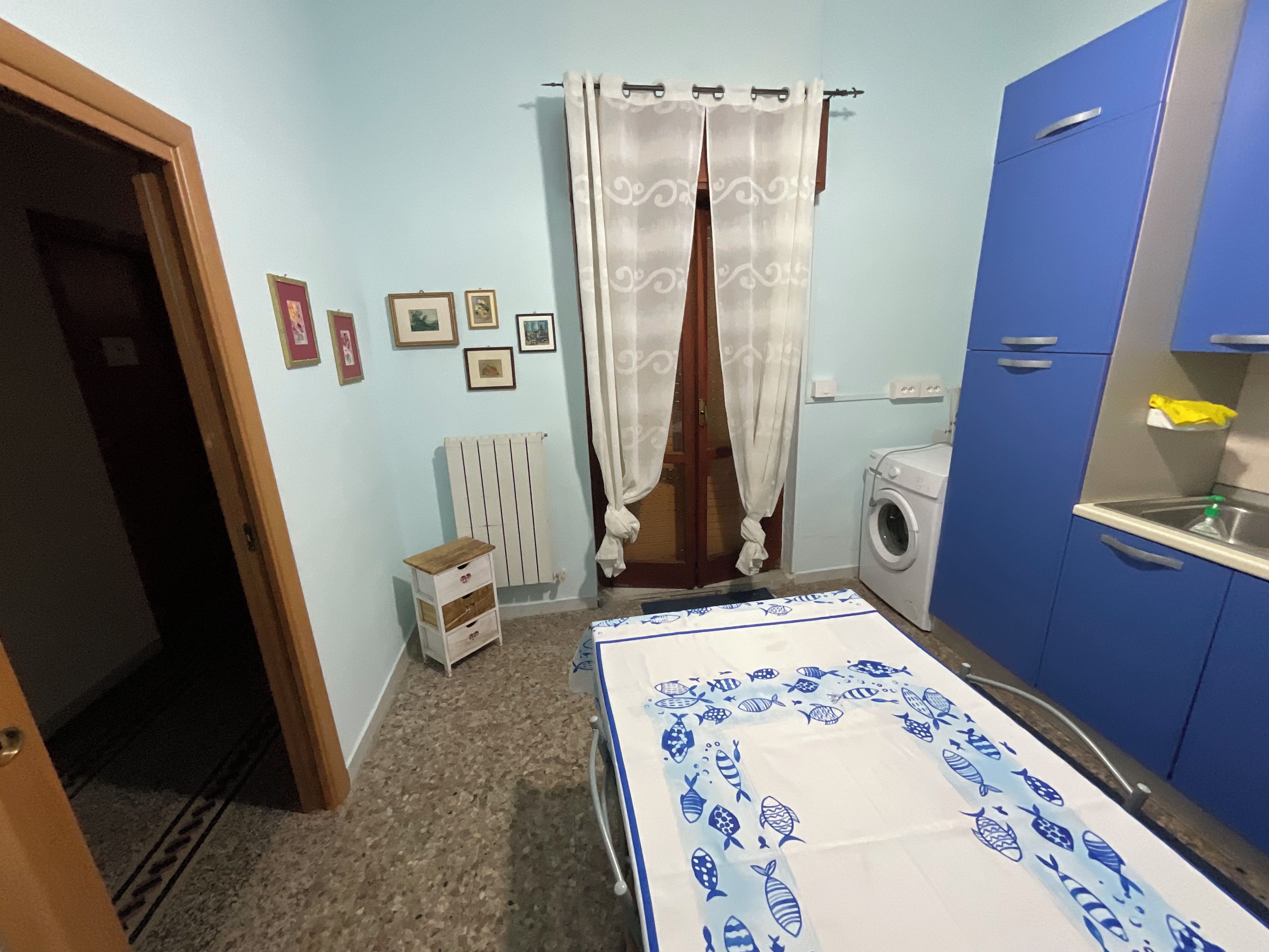 Ein Schlafzimmer mit einem Bett, einer Waschmaschine, einem Heizkörper und einem blauen Kleiderschrank.
