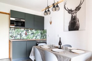 A modern kitchen with a dining area set for four. - Facing the slopes, 6-person apartment with terrace (Le Dévoluy)