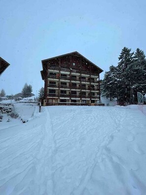 A multi-story building with a symmetrical facade, surrounded by snow-covered ground and trees. - Facing the slopes, 6-person apartment with terrace (Le Dévoluy)