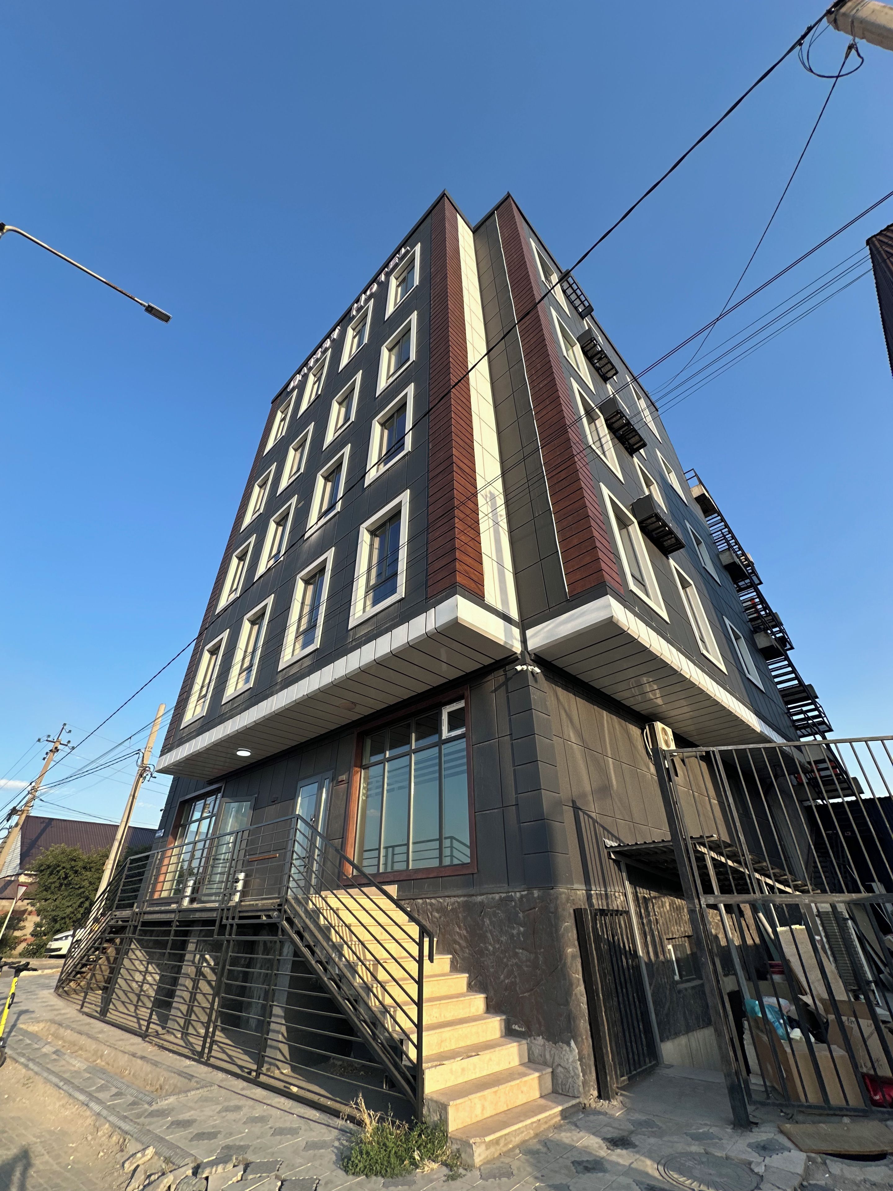 Un edificio de varios pisos con un diseño arquitectónico moderno, que destaca una escalera prominente que conduce a la entrada.