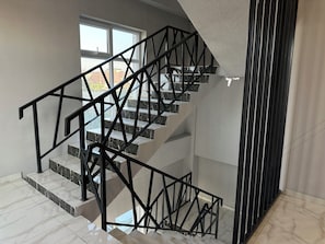 A modern interior with a spiral staircase, marble flooring, and a view through the windows. - Gatsby Lva Tolstogo (Bishkek)