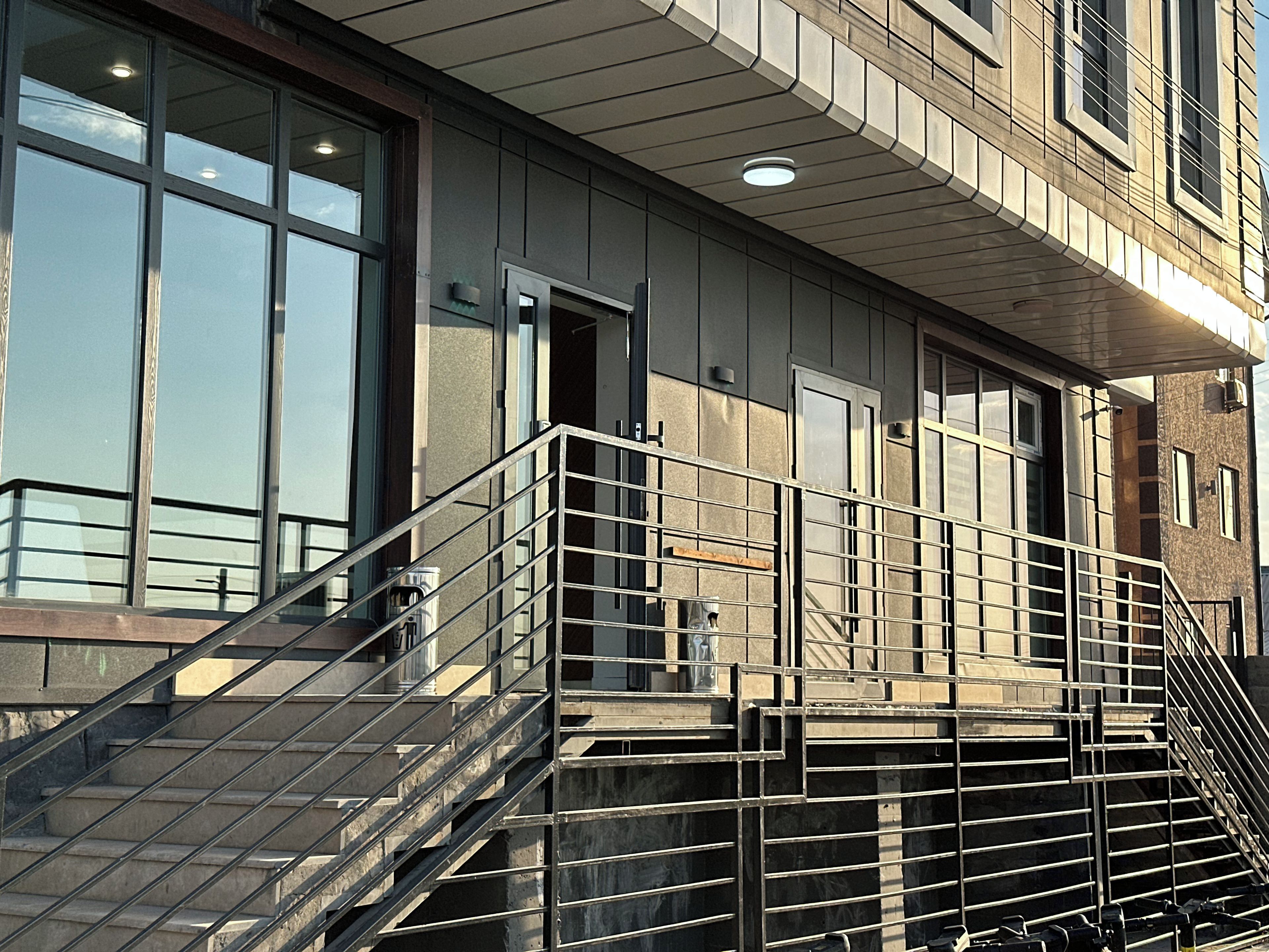 A building with a metal staircase leading to a balcony, large windows, and a door.