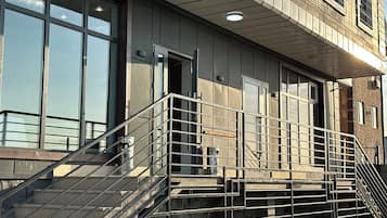 A building with a metal staircase leading to a balcony, large windows, and a door.