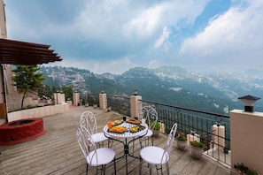Una terraza con una mesa lista para comer, con vistas a un paisaje montañoso.