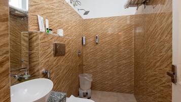 A bathroom with a marble wall, a sink, a toilet, and a shower area.