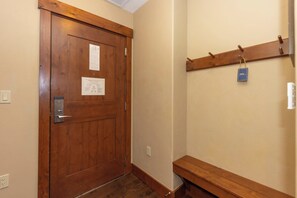 A wooden door with a metal handle and a notice on it. There is a wooden bench and a coat rack with a tag on the wall. - Peakside at One Ski Hill: Peak 8 Ski-In/Out, 2 Baths, A/C, Pools, Shuttle (Breckenridge)