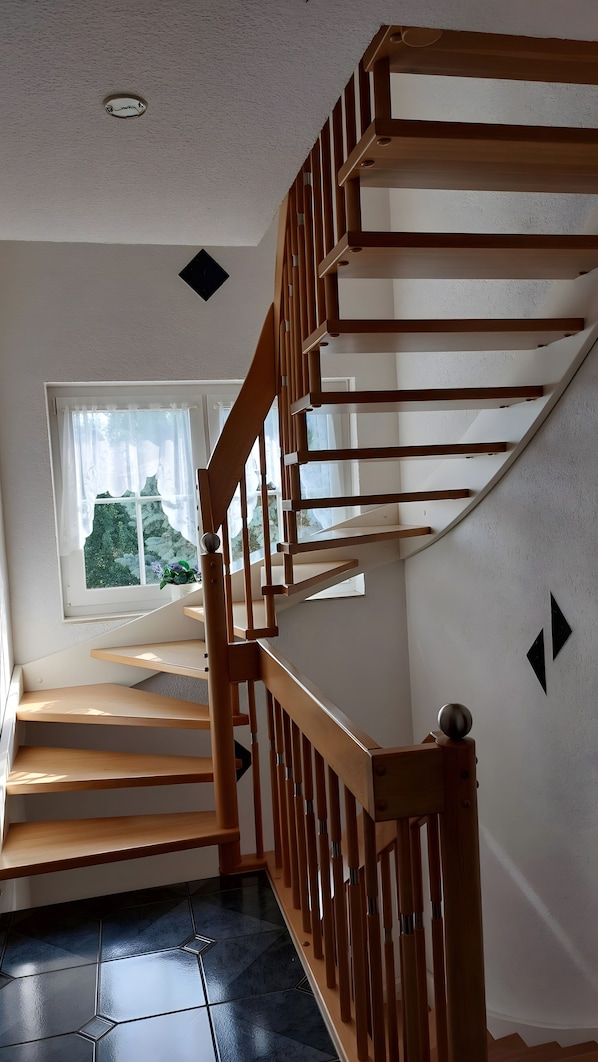 Eine Holztreppe mit Handlauf, die zu einer Zwischenebene führt.