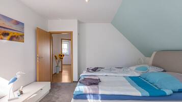 A bedroom with a bed, a bedside table, a dresser, a painting, and a vase with sunflowers.