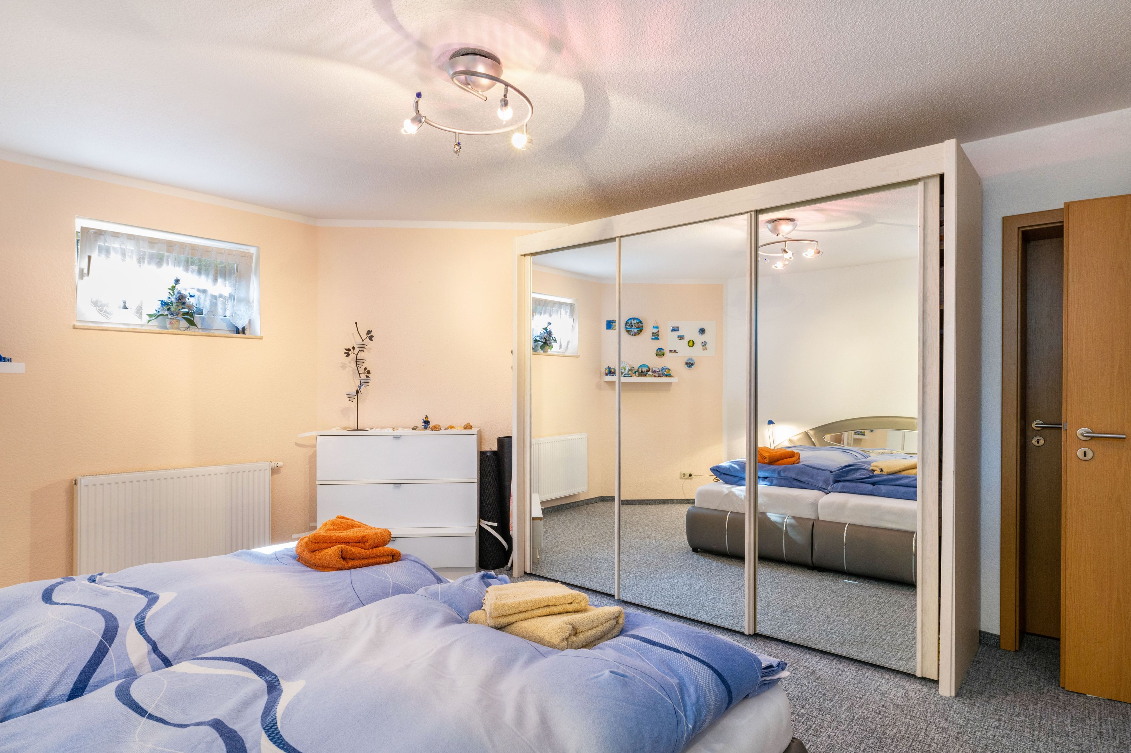 Habitación de hotel con cama, armario, espejo y lámpara en el techo.