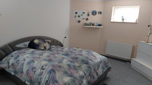 Ein Schlafzimmer mit einem Bett, einem Schminktisch, einer Heizung und Wanddekorationen.