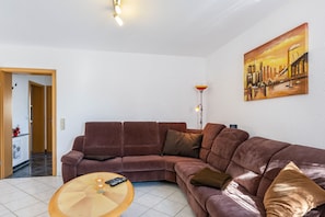 A living room with a brown sofa, a coffee table, a painting, and a lamp.
