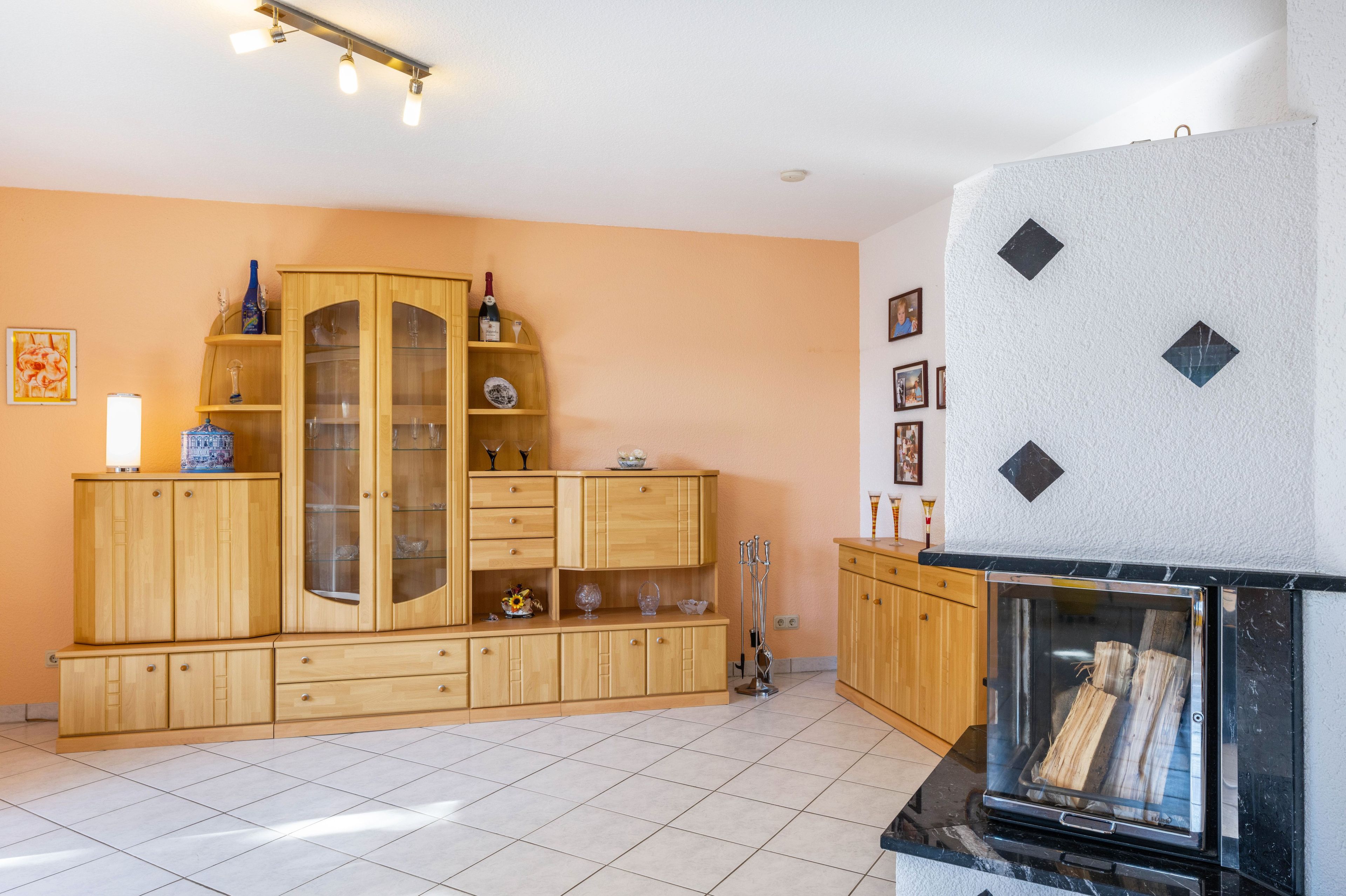 Una sala de estar con un mueble de madera, una chimenea y piso de baldosas.