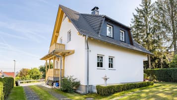 Ein zweistöckiges Haus mit einem geneigten Dach, einem Balkon und einem gepflegten Garten.