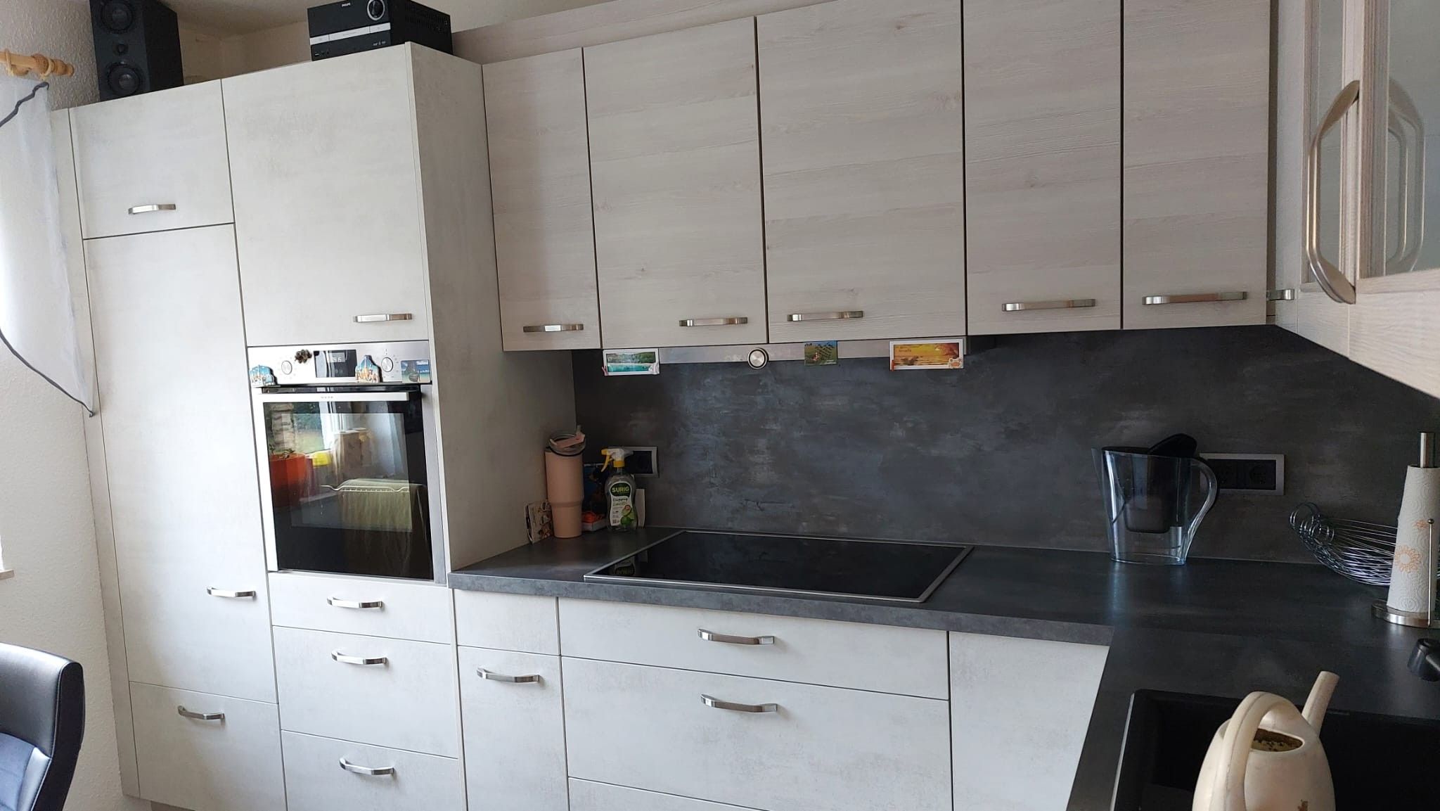 Cozinha moderna com armários brancos, forno embutido e bancada preta.