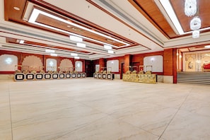 A spacious hotel lobby with a high ceiling, chandeliers, and a marble floor.