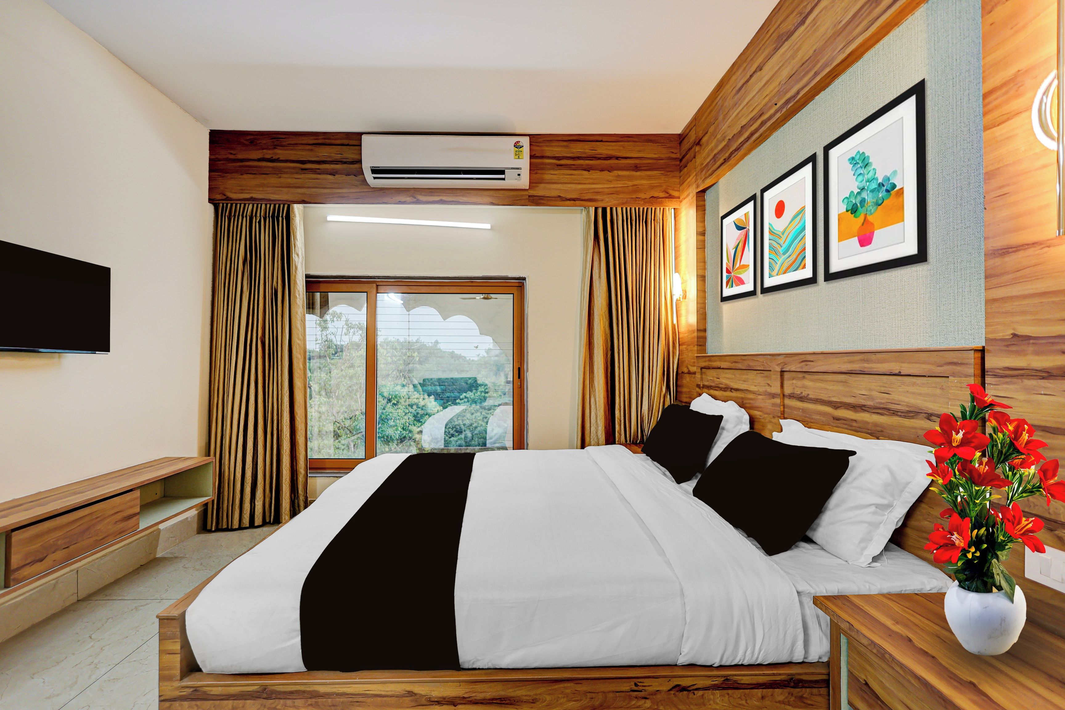 Ein Hotelzimmer mit Bett, Flachbildfernseher, Fenster mit Vorhängen und einem Kunstwerk an der Wand.