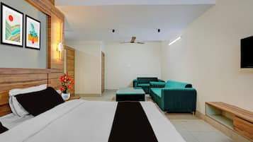A modern hotel room with a bed, a sofa, a TV, and artwork on the wall.