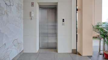 An elevator with a digital display, a lift sign above, and a wall with abstract line drawings.