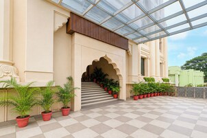 A building with a covered entrance, a staircase, and potted plants.