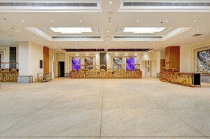 A spacious hotel lobby with a high ceiling, recessed lighting, and a central seating area with a decorative backdrop.
