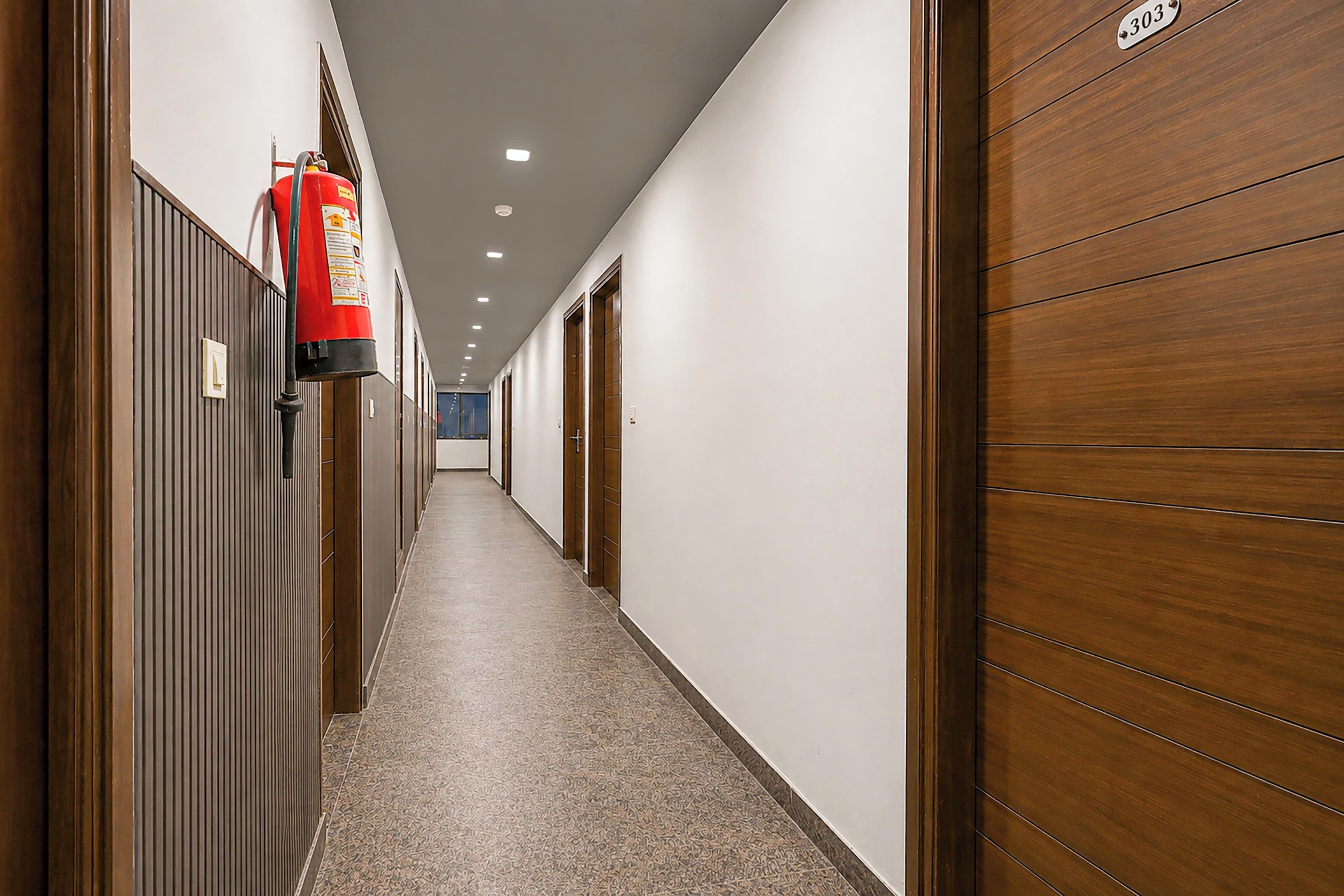 Un pasillo con puertas de madera y un extintor instalado en la pared.